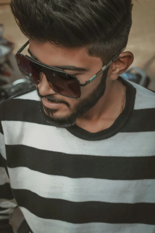 a man in a striped shirt looking at his cell phone, by Ahmed Yacoubi, trending on pexels, hurufiyya, wearing shades, picture of a male biker, headshot profile picture, indian