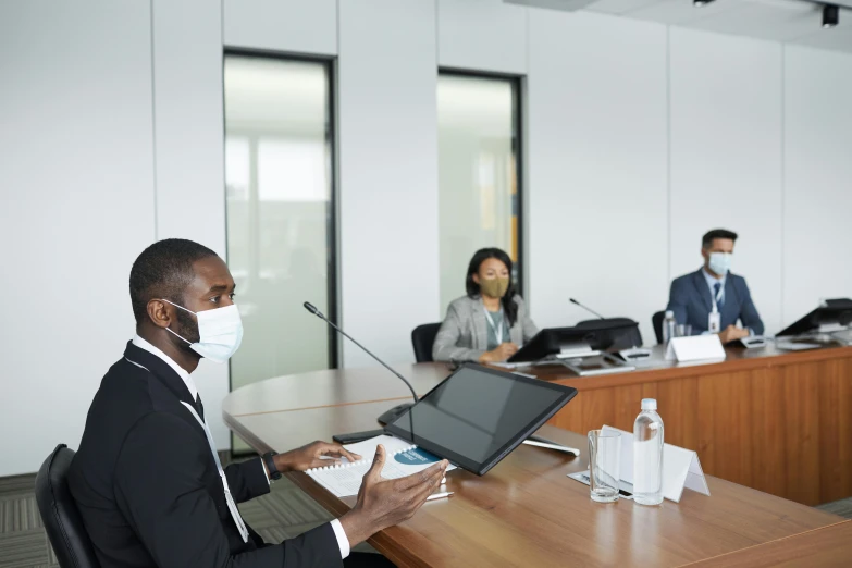 a man in a suit sitting at a table with a laptop, in a meeting room, emmanuel shiru, avatar image, gettyimages