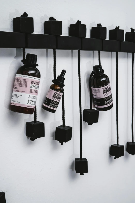 a bunch of bottles that are hanging on a wall, inspired by Caro Niederer, unsplash, kinetic art, skincare, programmable black goo, bedhead, product label