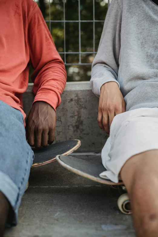 two men sitting next to each other with skateboards, trending on unsplash, varying ethnicities, closeup of arms, faded worn, gray men