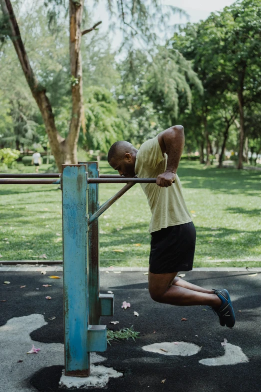 a man standing on top of a metal pole, working out, green spaces, square jaw-line, malaysian