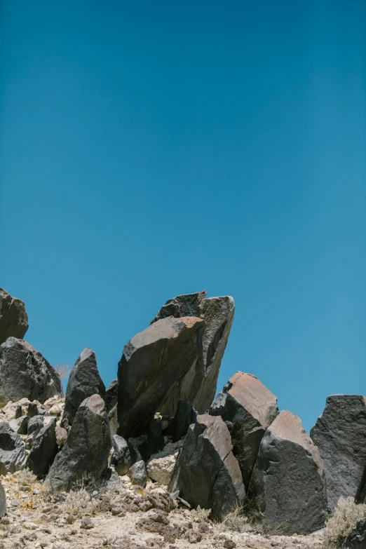 a man riding a snowboard on top of a rocky slope, an album cover, unsplash, minimalism, ((rocks)), cloudless blue sky, chile, slate