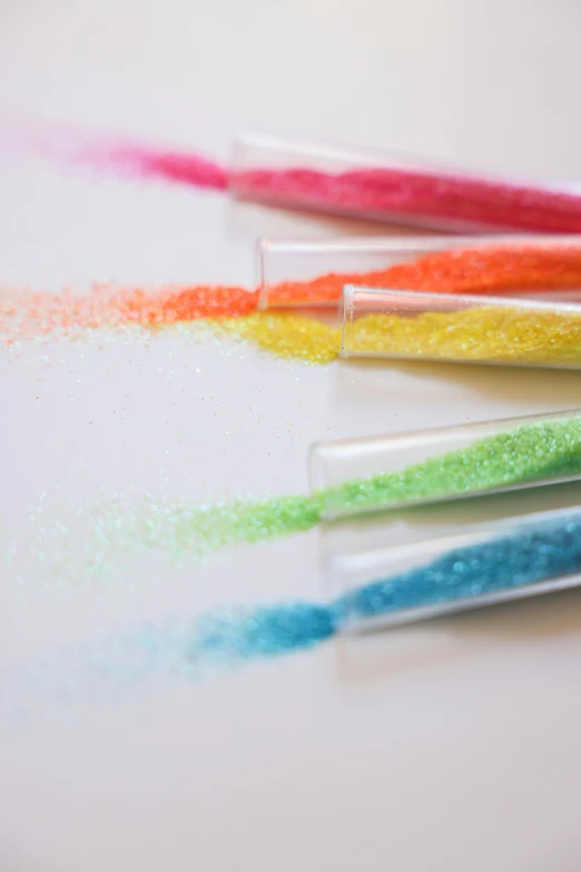 a group of toothbrushes sitting on top of a table, a stipple, inspired by George Aleef, close up of single sugar crystal, rainbow coloured rockets, chartreuse and orange and cyan, full of sand and glitter