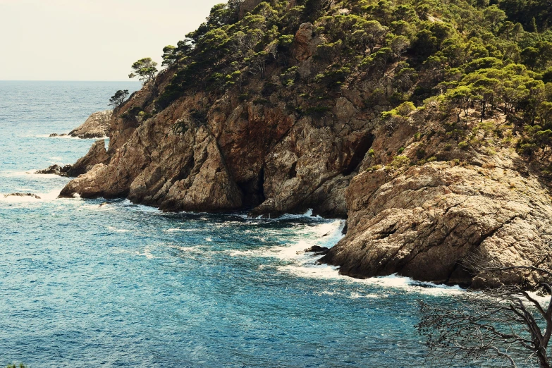 a large body of water next to a lush green hillside, a photo, ibiza, rocky cliff, cinematic film still, thumbnail