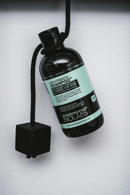 a bottle of hand sanitizer hanging from a cord, by Jens Søndergaard, black and teal paper, hair gel combed backwards, solar punk product photo, on clear background