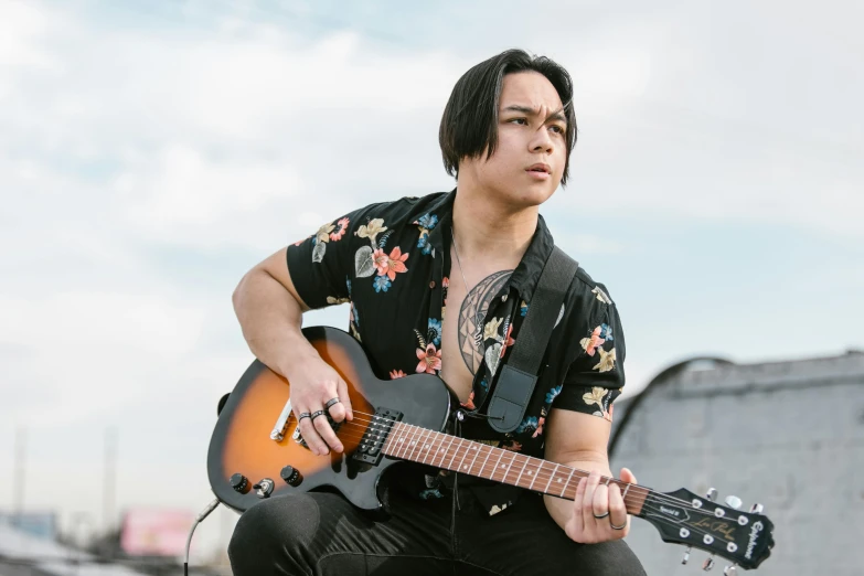 a man holding a guitar on top of a roof, an album cover, by Winona Nelson, pexels contest winner, shin hanga, an epic non - binary model, half asian, caleb from critical role, concert