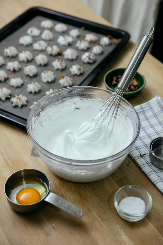 a wooden table topped with a bowl of batter and a whisk, baking cookies, whipped cream, promo image, whites