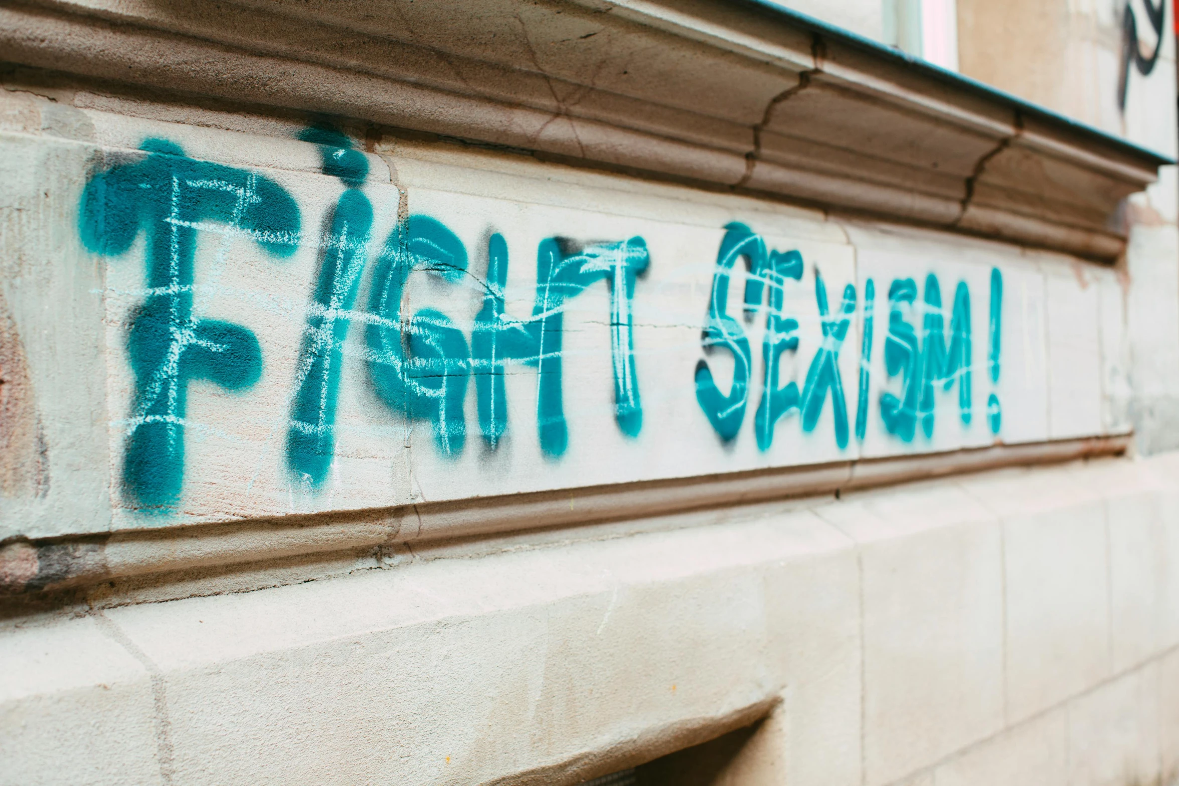 graffiti is spray painted on the side of a building, by Tracey Emin, trending on pexels, graffiti, activity with fight on swords, exist, street of teal stone, socialist