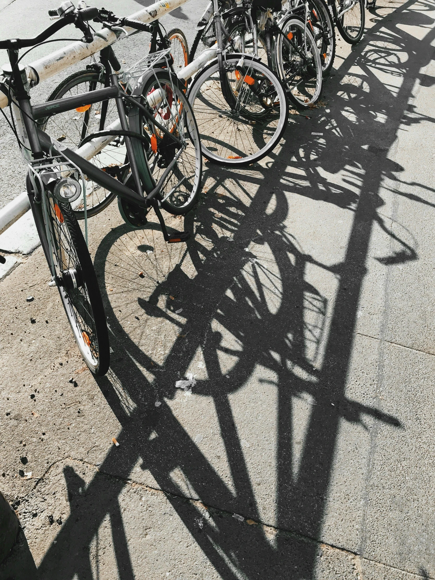 a row of bikes parked on the side of a road, by Matija Jama, pexels contest winner, occlusion shadow, flattened, detailed shadows, low quality photo