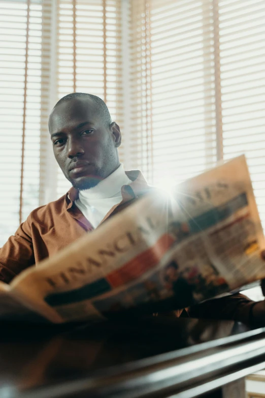 a man sitting at a table reading a newspaper, inspired by Gordon Parks, pexels contest winner, lance reddick, in a sunbeam, : kendrick lamar, adebanji alade