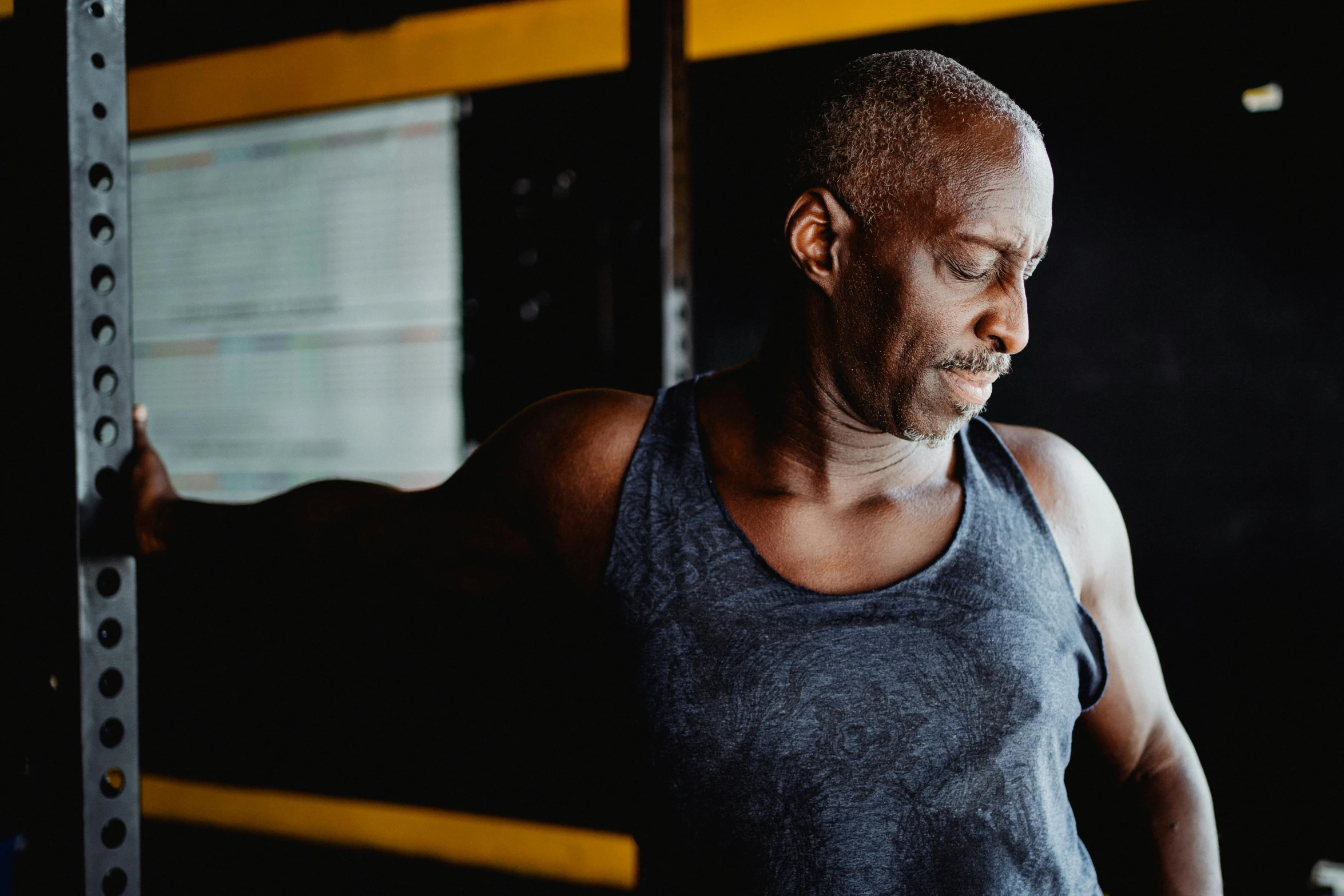 a man lifting a barbell in a gym, pexels contest winner, lance reddick, thoughtful expression, yellow and charcoal, weathered skin