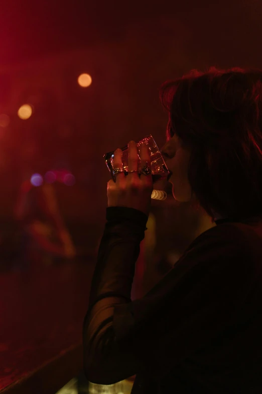 a woman sitting at a bar drinking from a glass, inspired by Nan Goldin, pexels, punk concert, with red haze, reylo kissing, uncropped