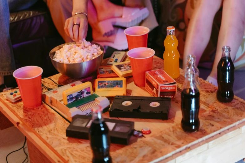 a group of people sitting around a wooden table, inspired by Nan Goldin, trending on pexels, happening, vhs artefacts, coke and chips on table, concert, old vintage vhs