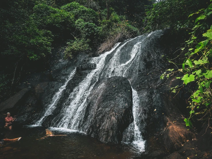 a man standing in front of a waterfall, pexels contest winner, hurufiyya, malaysia jungle, thumbnail, seen from afar, bathing in a waterfall