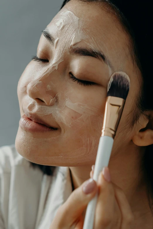 a woman brushes her face with a brush, trending on pexels, hyperrealism, detailed face with mask, young asian girl, square facial structure, pleasing