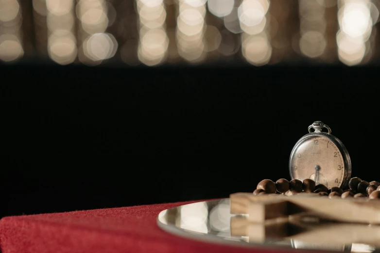 a silver pocket watch sitting on top of a red table, a still life, by Julia Pishtar, pexels contest winner, anamorphic bokeh, snacks, arabian night, sitting on a mocha-colored table