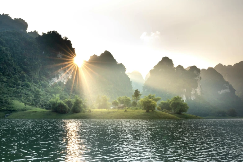 a large body of water with mountains in the background, by Raymond Han, pexels contest winner, romanticism, asian sun, karst landscape, sun flare, lush surroundings
