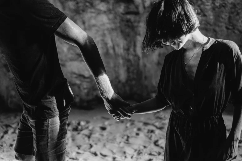 a black and white photo of a man and a woman holding hands, a black and white photo, by Kristian Zahrtmann, pexels, figuration libre, lost in a cave, with violence, woman holding another woman, adrien girod