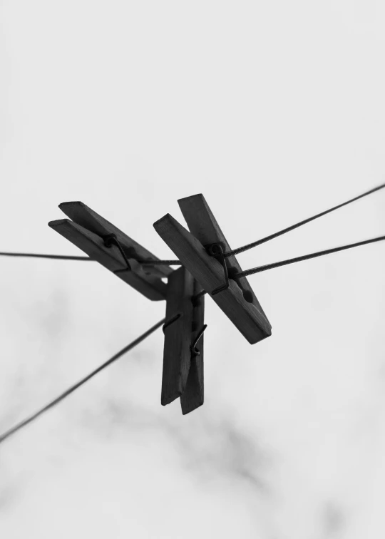 a black and white photo of clothes pegs on a wire, by Adam Marczyński, symmetric!, two hang, stacked, fly