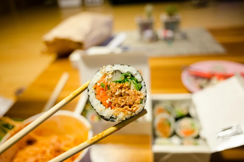 a close up of a person holding chopsticks over a sushi, inspired by Maki Haku, unsplash, shin hanga, 🦩🪐🐞👩🏻🦳, low - angle shot, blurred, family photo