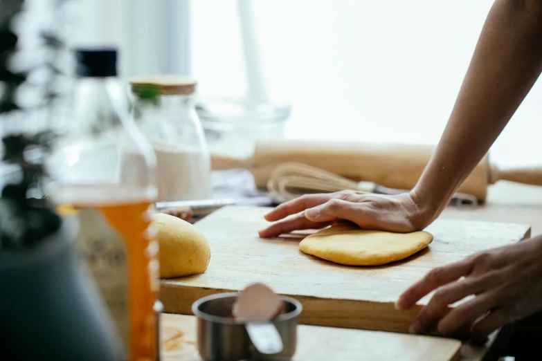 a person kneads a piece of bread on a cutting board, a still life, trending on pexels, animation, steamed buns, vannessa ives, pizza on a table