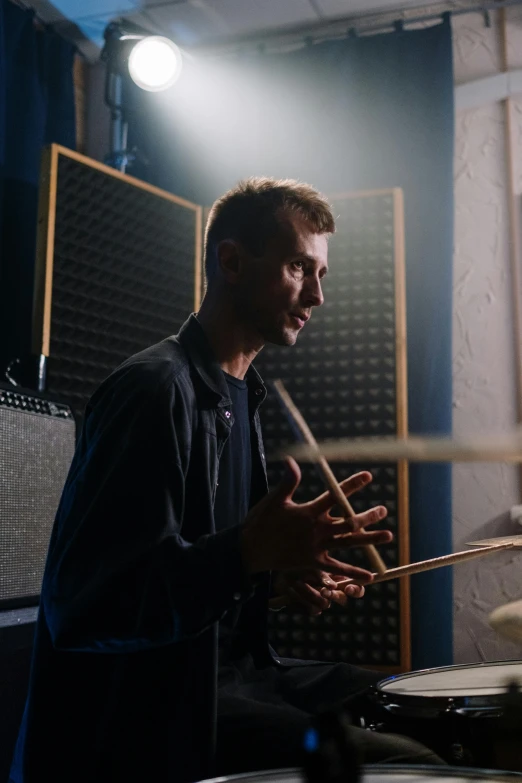 a man playing drums in a recording studio, an album cover, unsplash, bauhaus, holding wands, looking to the side off camera, **cinematic, rectangle