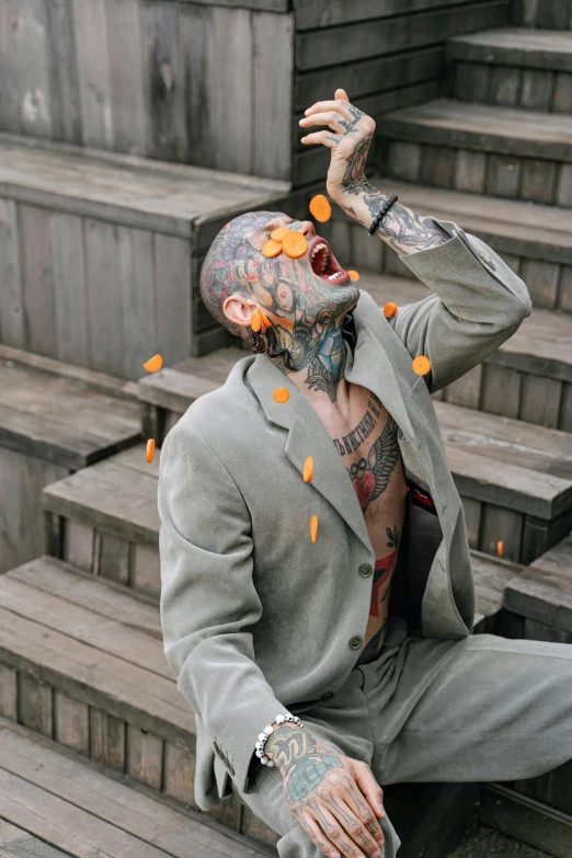 a man with tattoos on his face sitting on steps, inspired by Elsa Bleda, pexels contest winner, renaissance, falling petals, wearing tight suit, megan fox made out of mayonnaise, orange demons