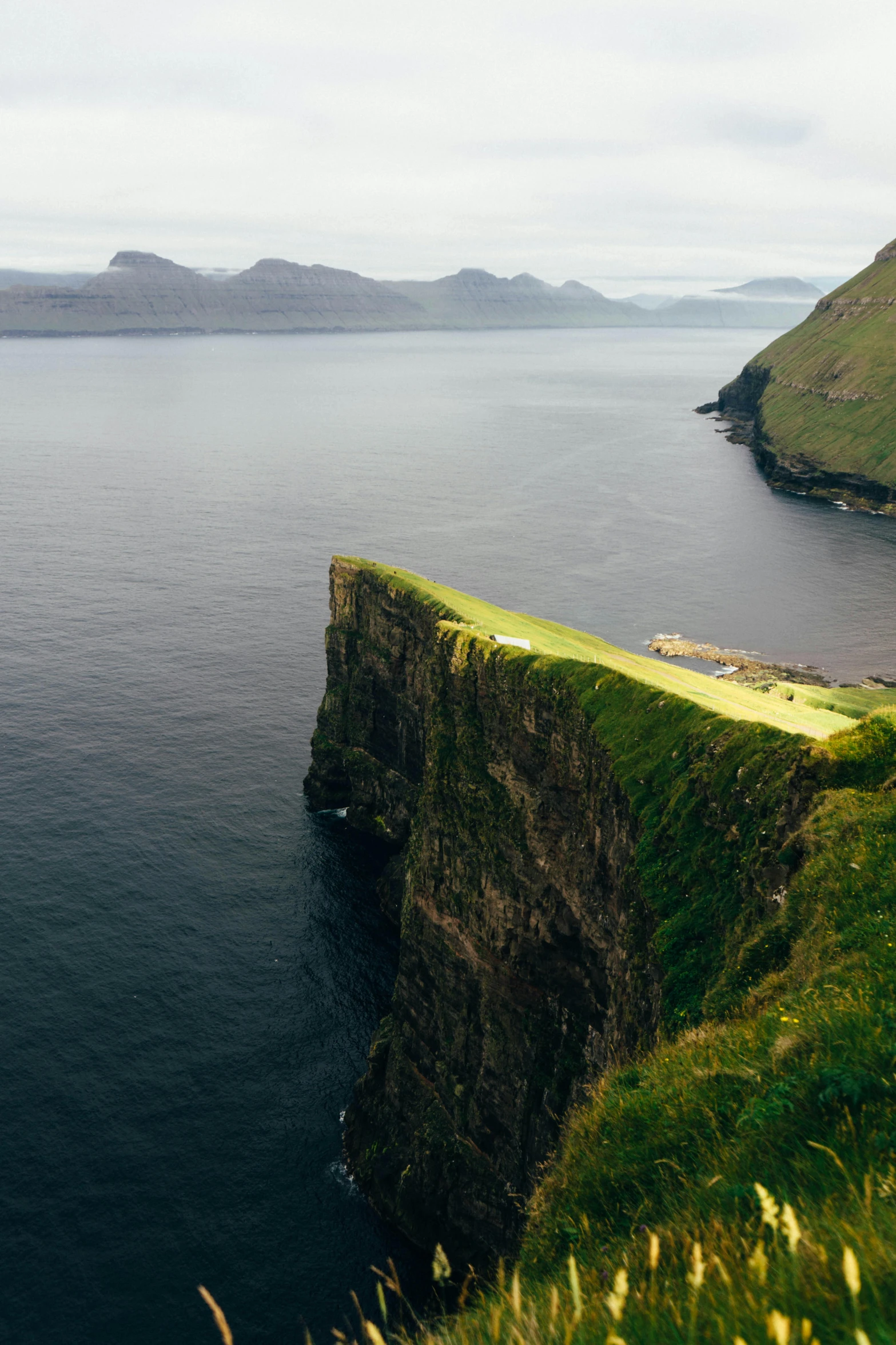 a large body of water sitting on top of a lush green hillside, by Johannes Voss, coastal cliffs, dessert, iconic