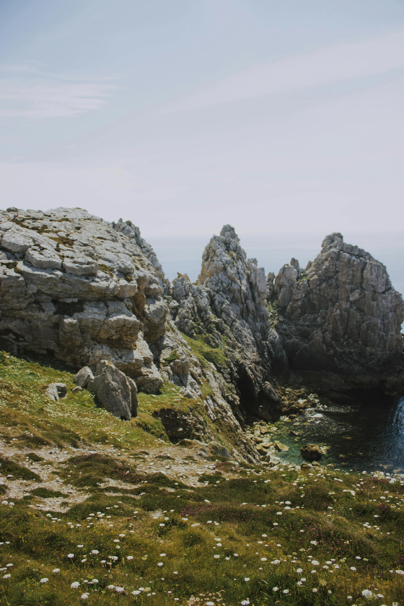 a large body of water sitting on top of a lush green hillside, by Juan Giménez, unsplash, les nabis, rocky coast, asymmetrical spires, low quality photo, granite