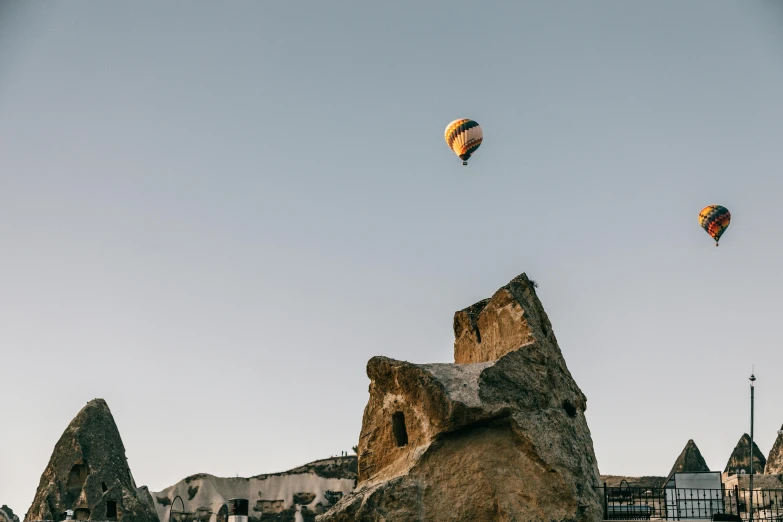 a group of hot air balloons flying over a rocky landscape, unsplash contest winner, buildings carved out of stone, mid shot photo, jump, 15081959 21121991 01012000 4k