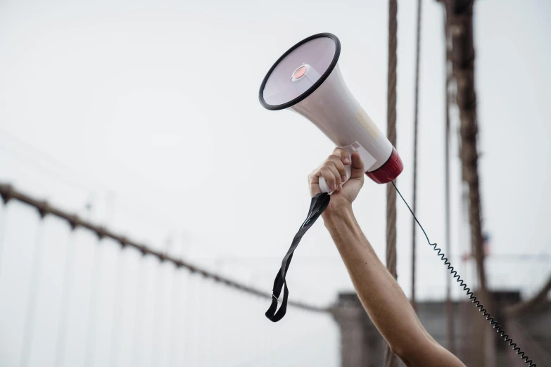 a person holding a megaphone in front of a bridge, unsplash, holding a thick staff, 15081959 21121991 01012000 4k, without text, environmental shot