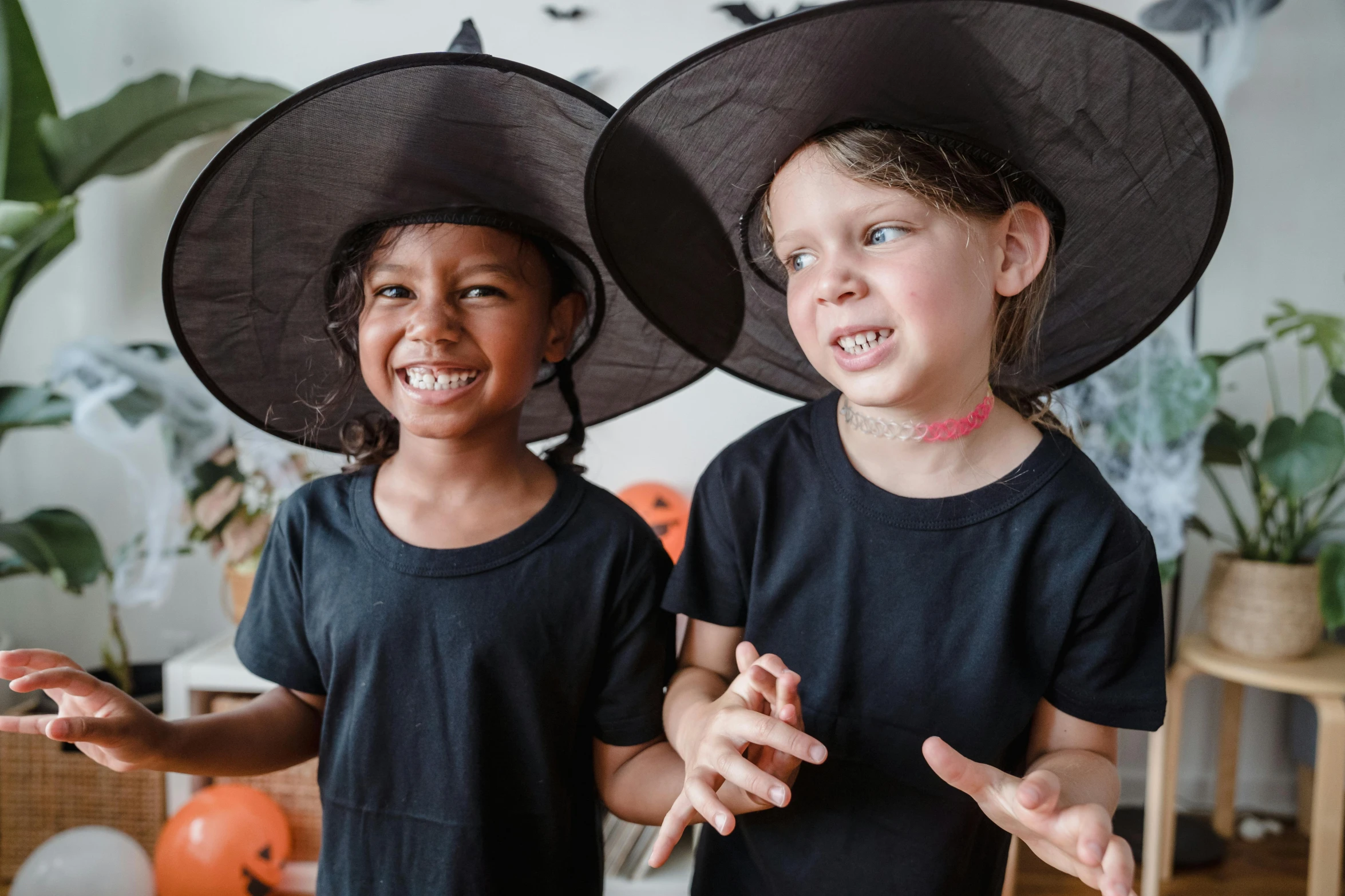 two little girls wearing witch hats standing next to each other, pexels contest winner, avatar image, smiling playfully, black, promotional image