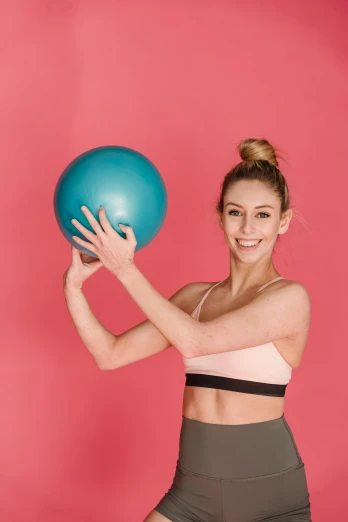 a woman holding a blue ball in front of her face, a colorized photo, trending on pexels, sports bra, shrugging arms, pink body, profile image