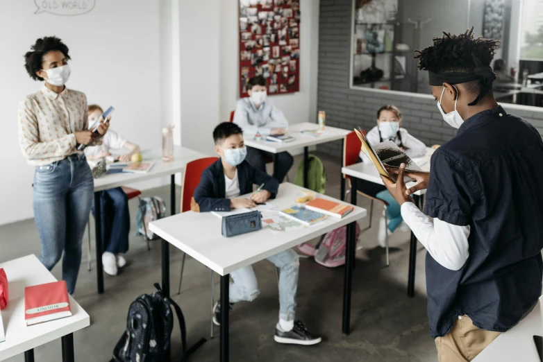 a group of people sitting at desks in a classroom, a picture, pexels contest winner, masked person in corner, kid, standing on a desk, profile image