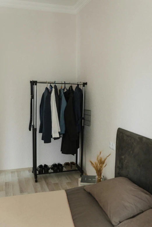a bed room with a neatly made bed, by Adam Marczyński, unsplash, minimalism, techwear clothes, rack, wearing a long coat, 15081959 21121991 01012000 4k