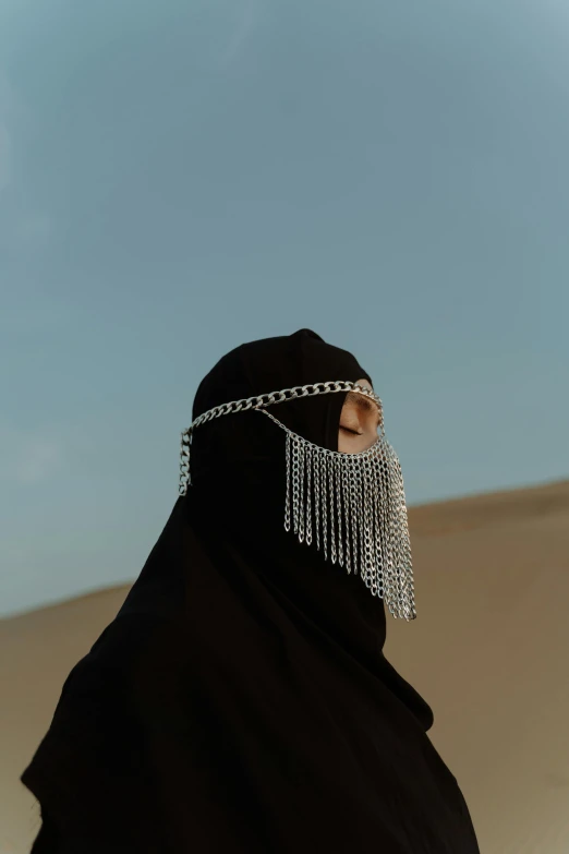 a woman wearing a black hijab in the desert, an album cover, inspired by Hedi Xandt, trending on pexels, chain mail, no face, sultan, chains