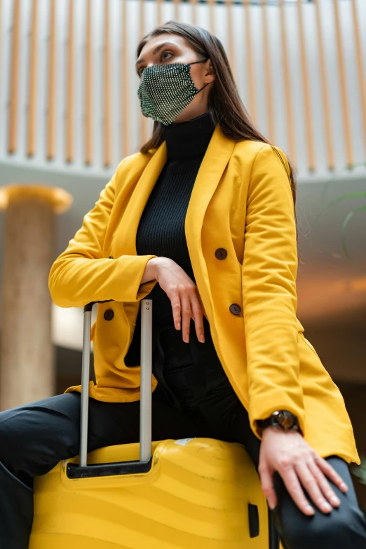 a woman sitting on top of a yellow suitcase, trending on pexels, renaissance, wearing a turtleneck and jacket, wearing mask, sitting on designer chair, wearing a blazer