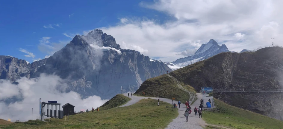 a group of people walking up the side of a mountain, pexels contest winner, les nabis, lauterbrunnen valley, large clouds visible, avatar image, mountains of ice cream