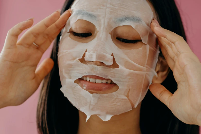 a woman putting a sheet mask on her face, trending on pexels, mingei, background image, slightly smiling, ahegao face, square face