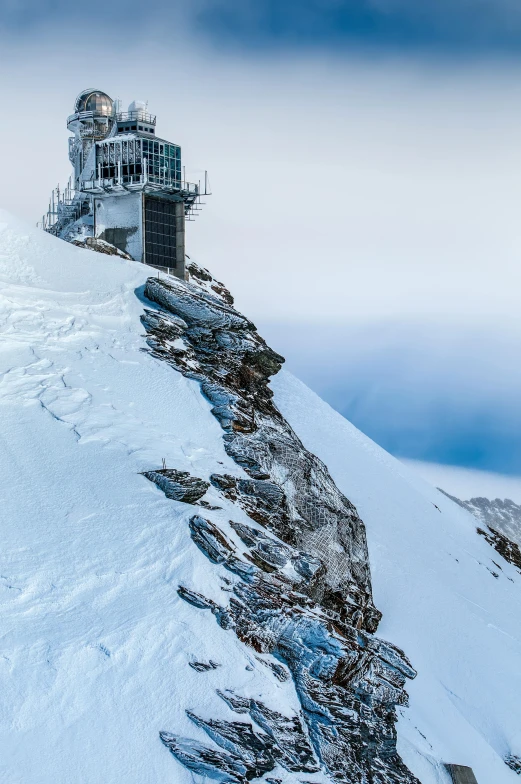 a man standing on top of a snow covered mountain, swiss architecture, watch tower, award - winning photo ”, 8k resolution”