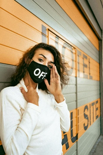 a woman in a white shirt and a black face mask, a photo, inspired by Elsa Bleda, trending on pexels, graffiti, off-white, hotel room, promotional image, doff