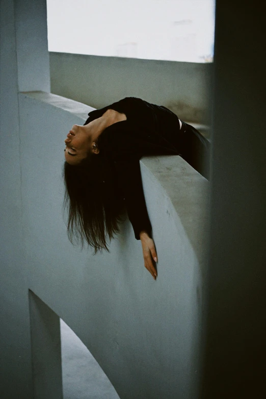 a woman that is laying down on a ledge, by Maciej Kuciara, arabesque, looking down on the camera, stretching to walls, heartbreak, standing sideways