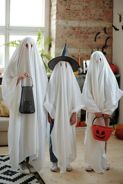 three children dressed in halloween costumes standing in a living room, an album cover, pexels, dressed in white robes, helmet is off, ( ( theatrical ) ), ghost children