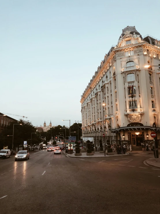 a large white building sitting on the side of a road, by Emma Andijewska, pexels contest winner, art nouveau, city street at dusk, madrid, wide high angle view, “diamonds