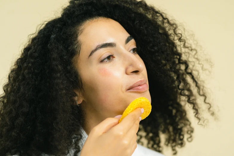 a woman taking a bite of a banana, a digital rendering, trending on pexels, happening, oiled skin, sponge, yellow-orange, aida muluneh