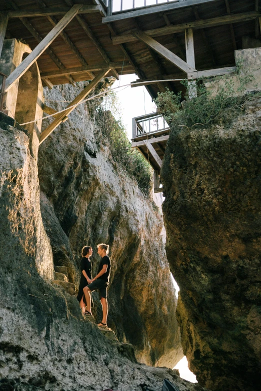 a couple of people standing on top of a cliff, walkways, natural cave wall, bali, mezzanine