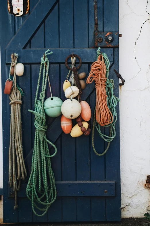 a door with a bunch of buoys hanging on it, a still life, by Jessie Algie, unsplash, charts, navy, seasonal, ropes
