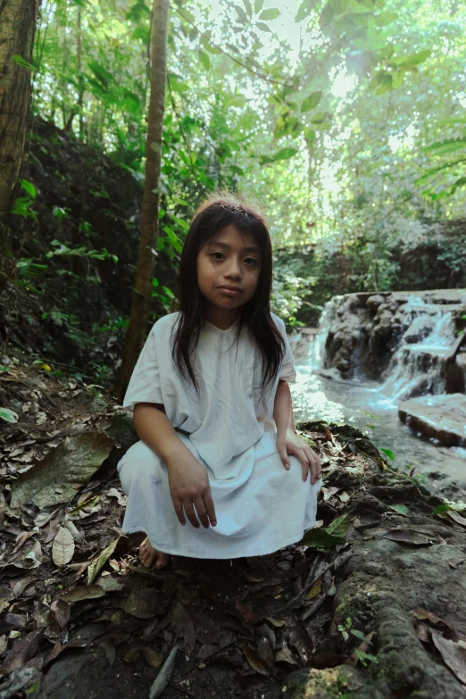 a little girl sitting on a log in the woods, an album cover, by reyna rochin, sumatraism, video still, (waterfall), indigenous, portrait shot 8 k