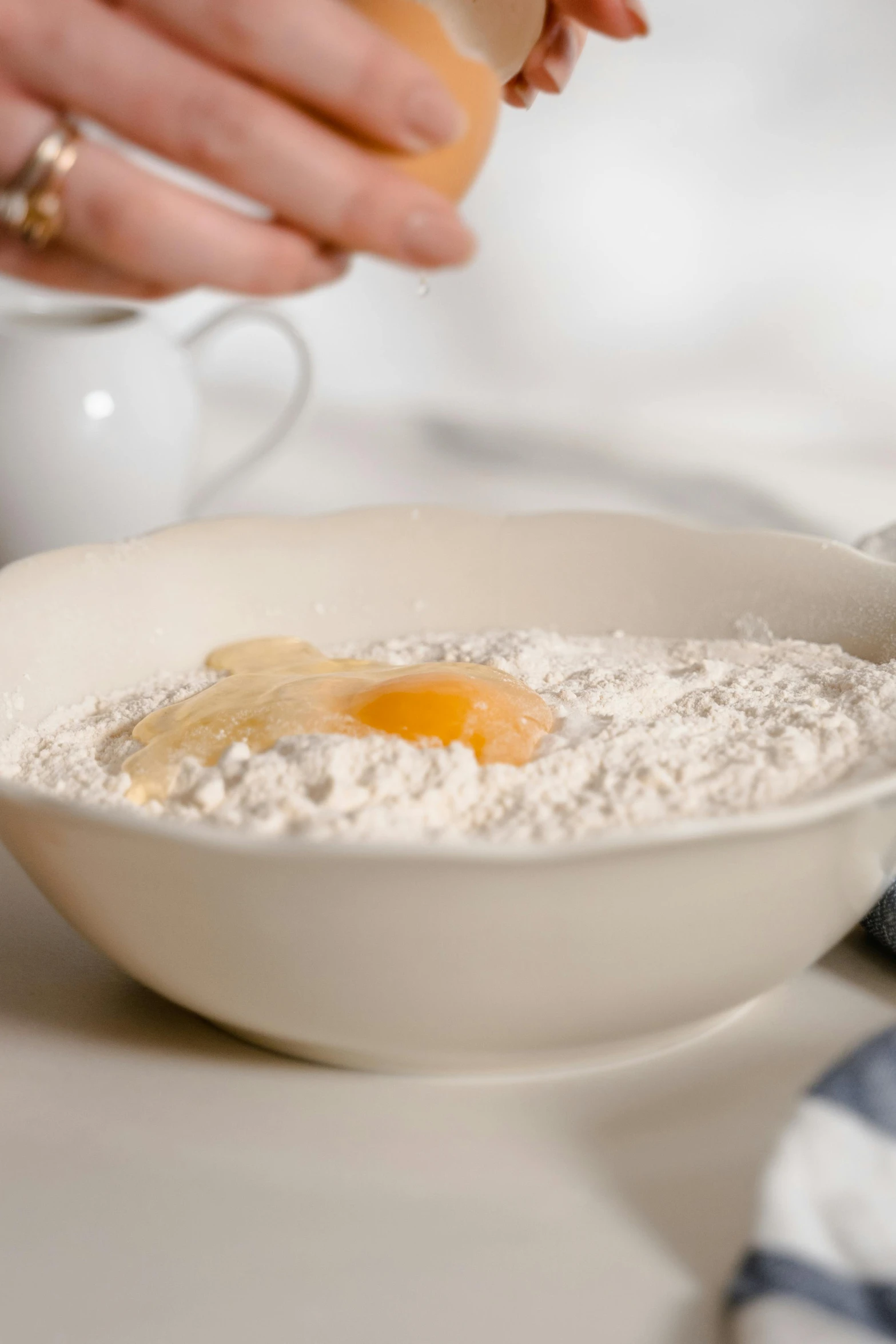 a person adding an egg into a bowl of flour, inspired by Josefina Tanganelli Plana, detailed product image, detail shot, petite, cascade