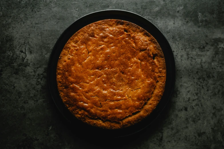 a cake sitting on top of a pan on a table, unsplash, hurufiyya, baked bean skin texture, front view dramatic, round format, slim